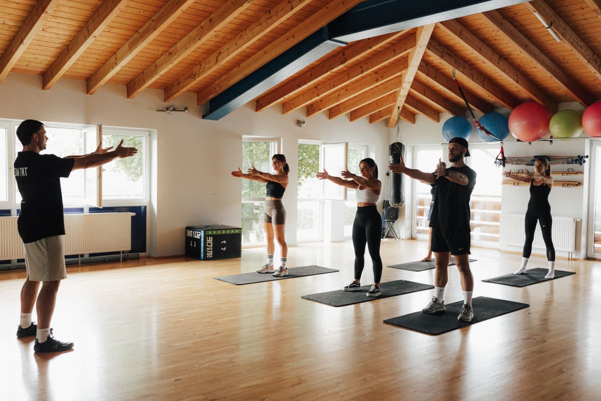 Ein Trainer zeigt einer Gruppe im Kursraum des TNT Fitness eine Übung
